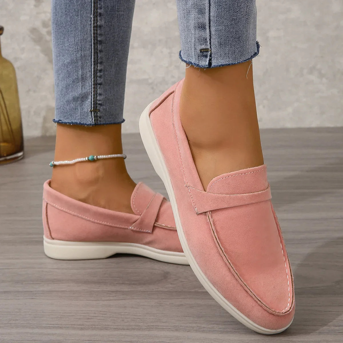 Pink suede slip-on loafers with moc-toe stitching and white rubber sole