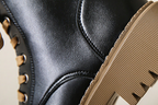 Women's black boot with side-zip detail and textured tread platform sole close-up