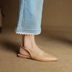 Beige leather slingback flats on model’s feet with pointed toe and low sole
