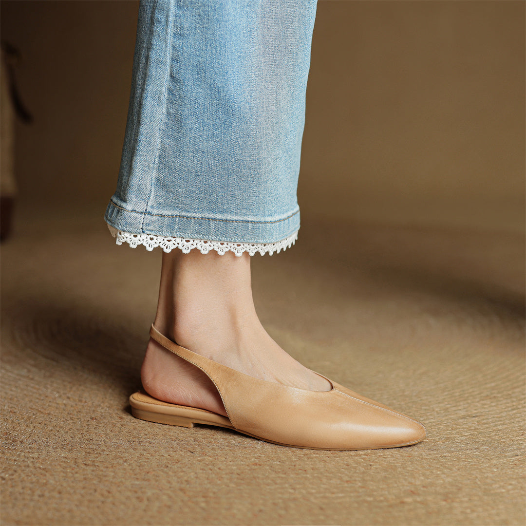 Beige leather slingback flats on model’s feet with pointed toe and low sole
