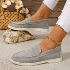 Grey suede slip-on loafers with moc-toe stitching and white rubber sole