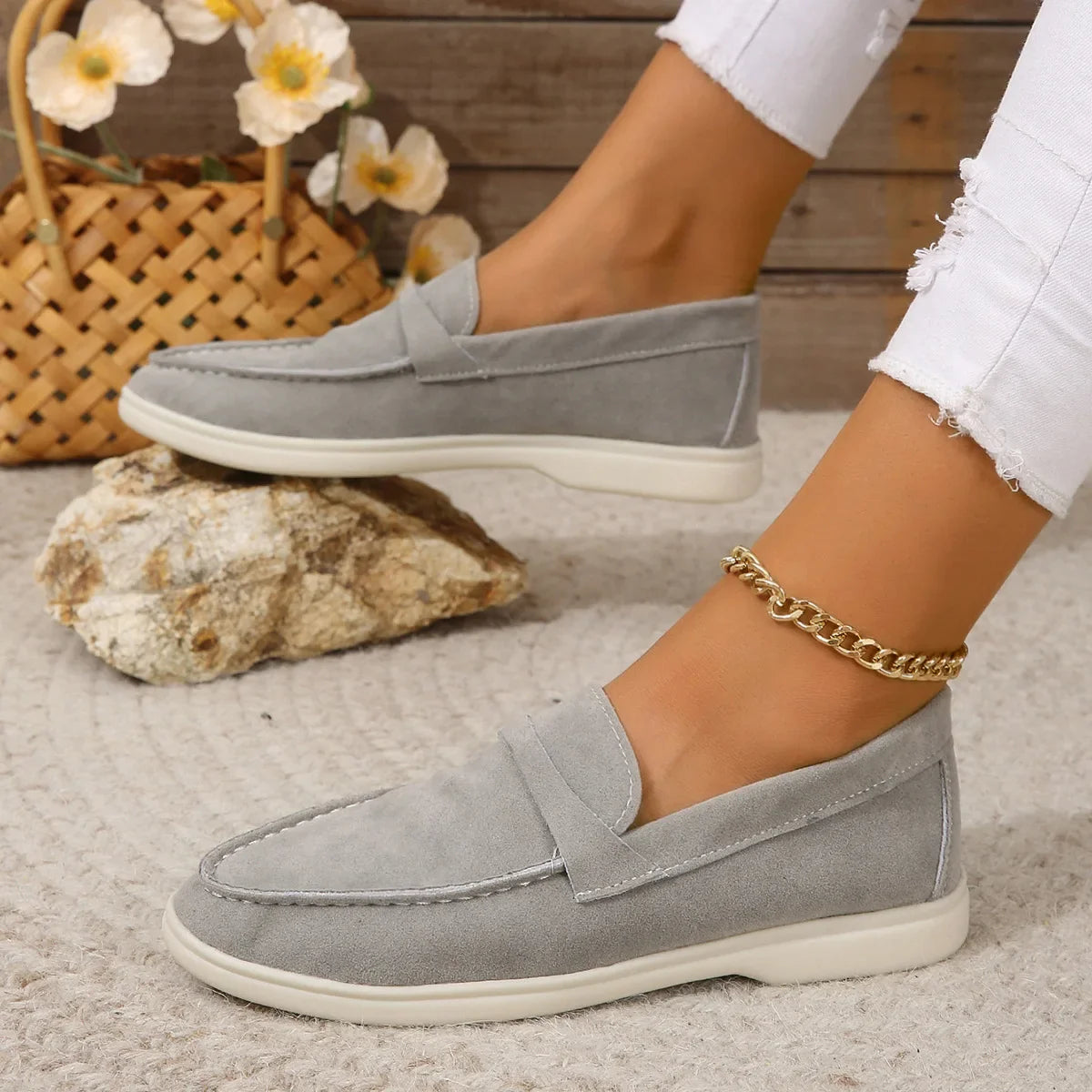Grey suede slip-on loafers with moc-toe stitching and white rubber sole