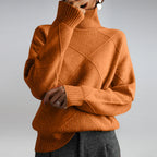 Women’s cashmere turtleneck sweater in rust orange, ribbed collar and textured diamond pattern.