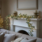 Eucalyptus garland with warm LED lights along white fireplace mantel and hearth