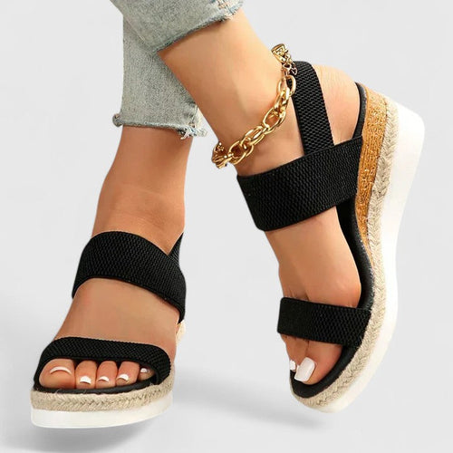 Black two-strap platform sandals with open toe and jute midsole, ankle chain detail