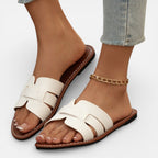Women’s leather slide sandals, open toe, white wide straps, flat cushioned sole with stitched edge.