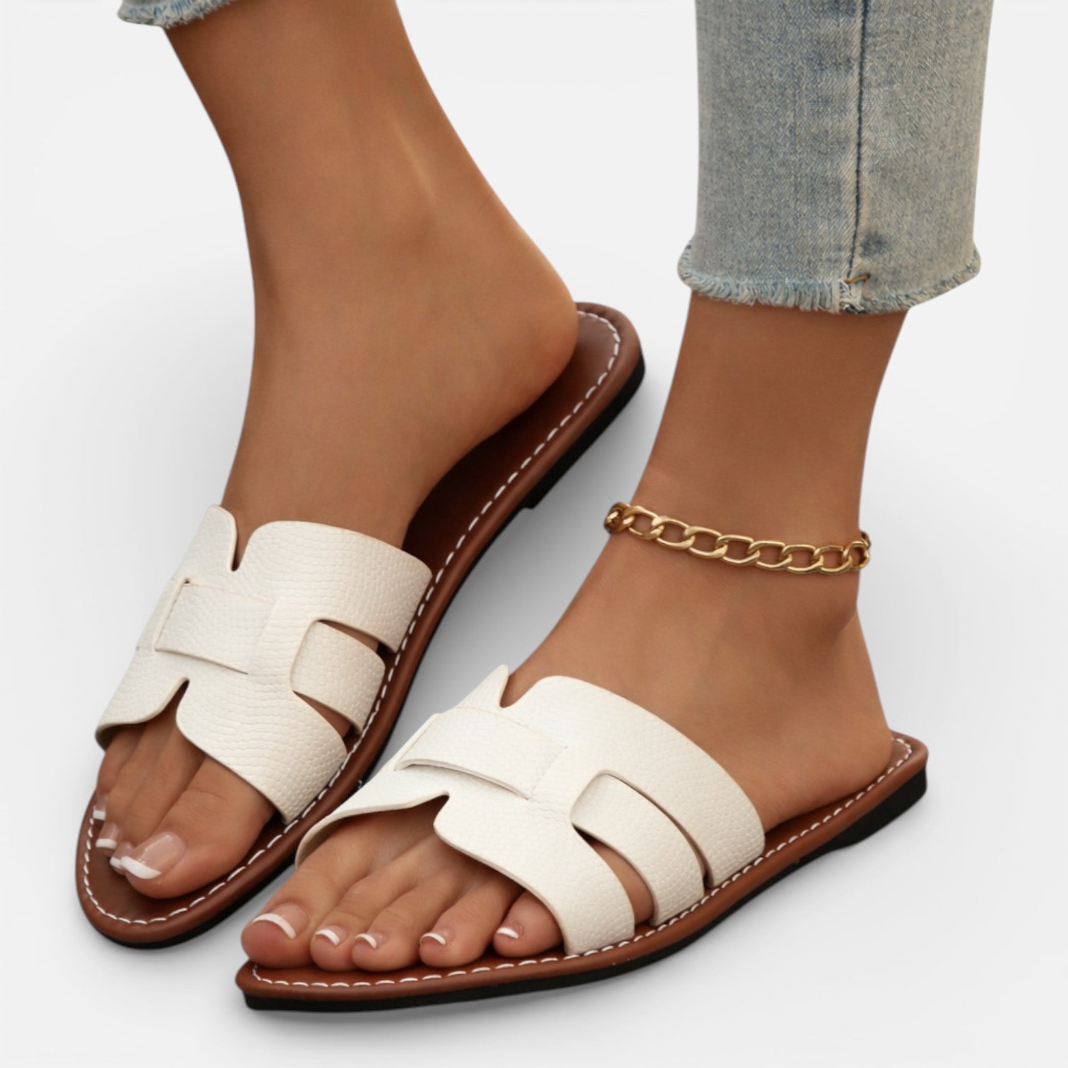Women’s leather slide sandals, open toe, white wide straps, flat cushioned sole with stitched edge.