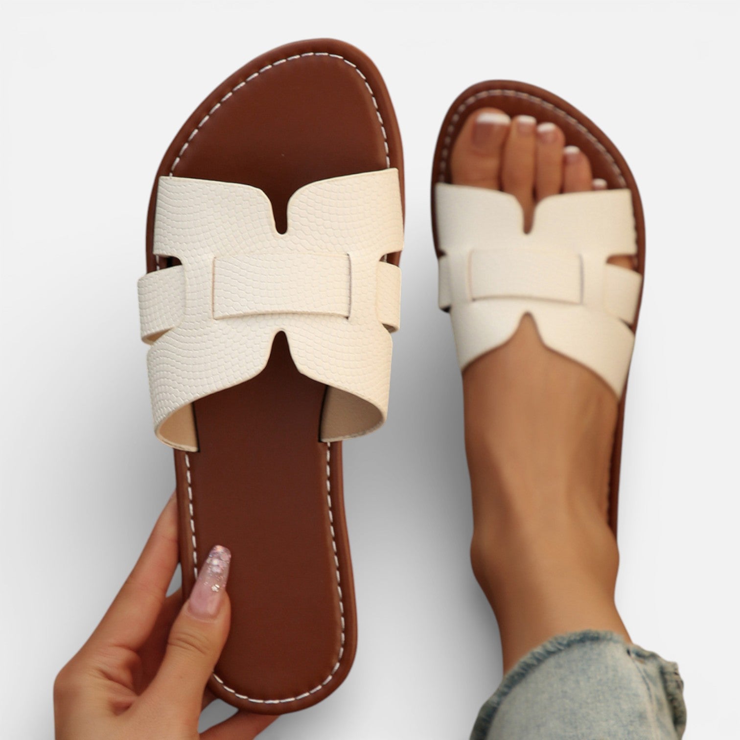 Women’s leather slide sandals, open toe, wide white strap with stitched detailing, cushioned footbed.
