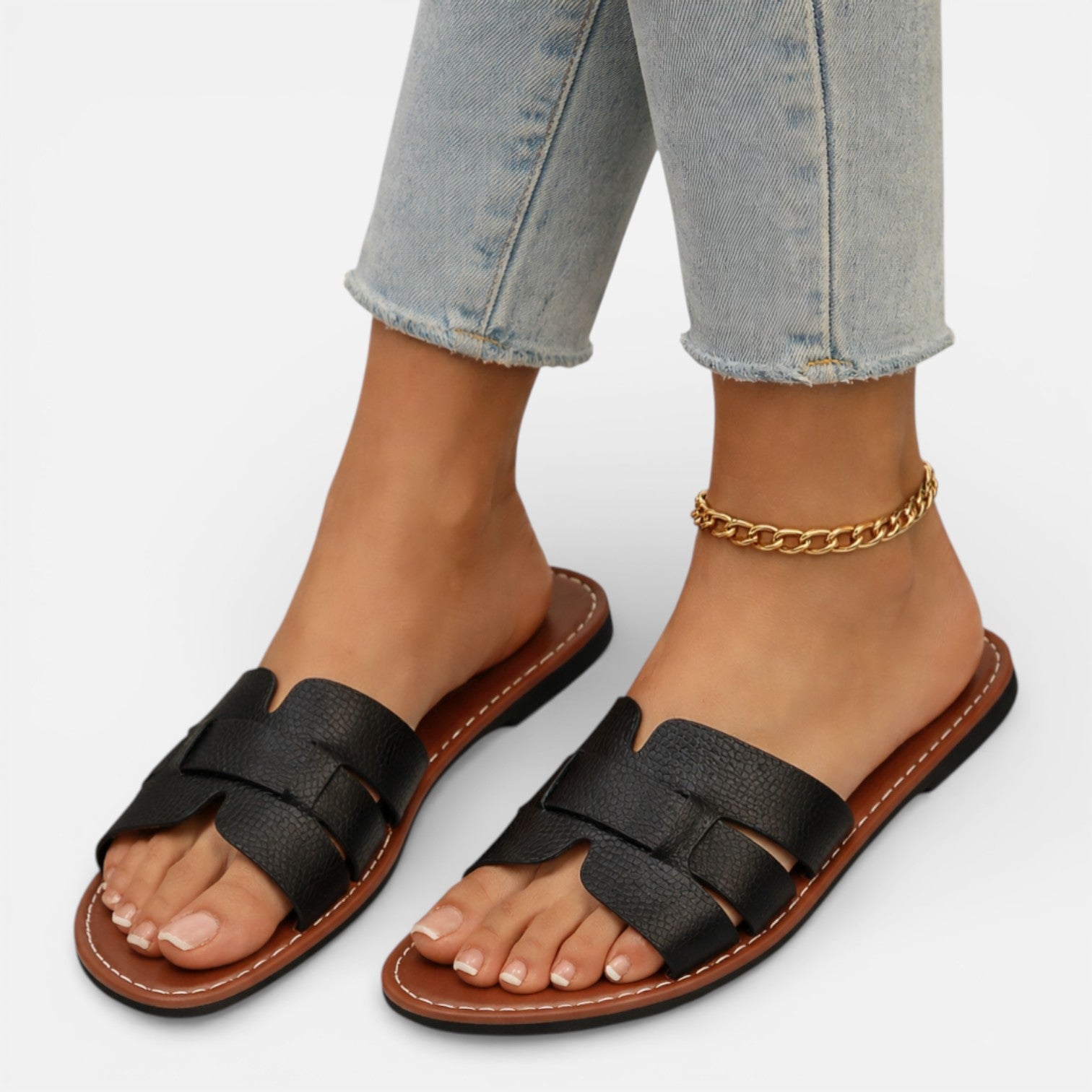 Women’s leather slide sandals, open toe, black wide straps and ankle chain, flat cushioned sole.