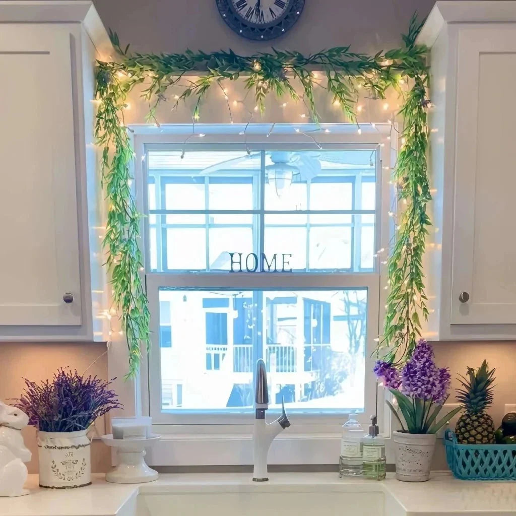 green leaf garland draped above a window with warm string lights