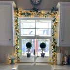 green leaf garland with warm fairy lights framing a kitchen window ledge