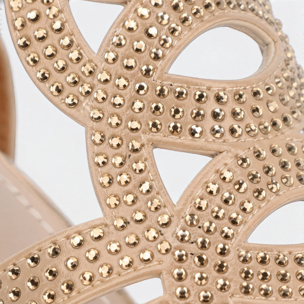 Close-up of beige openwork sandal upper with gold-tone stud details