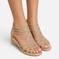 Women’s beige sandals on feet, open toe with cutout straps and wedge sole