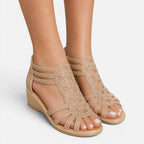 Women’s beige sandals on feet, open toe with cutout straps and wedge sole