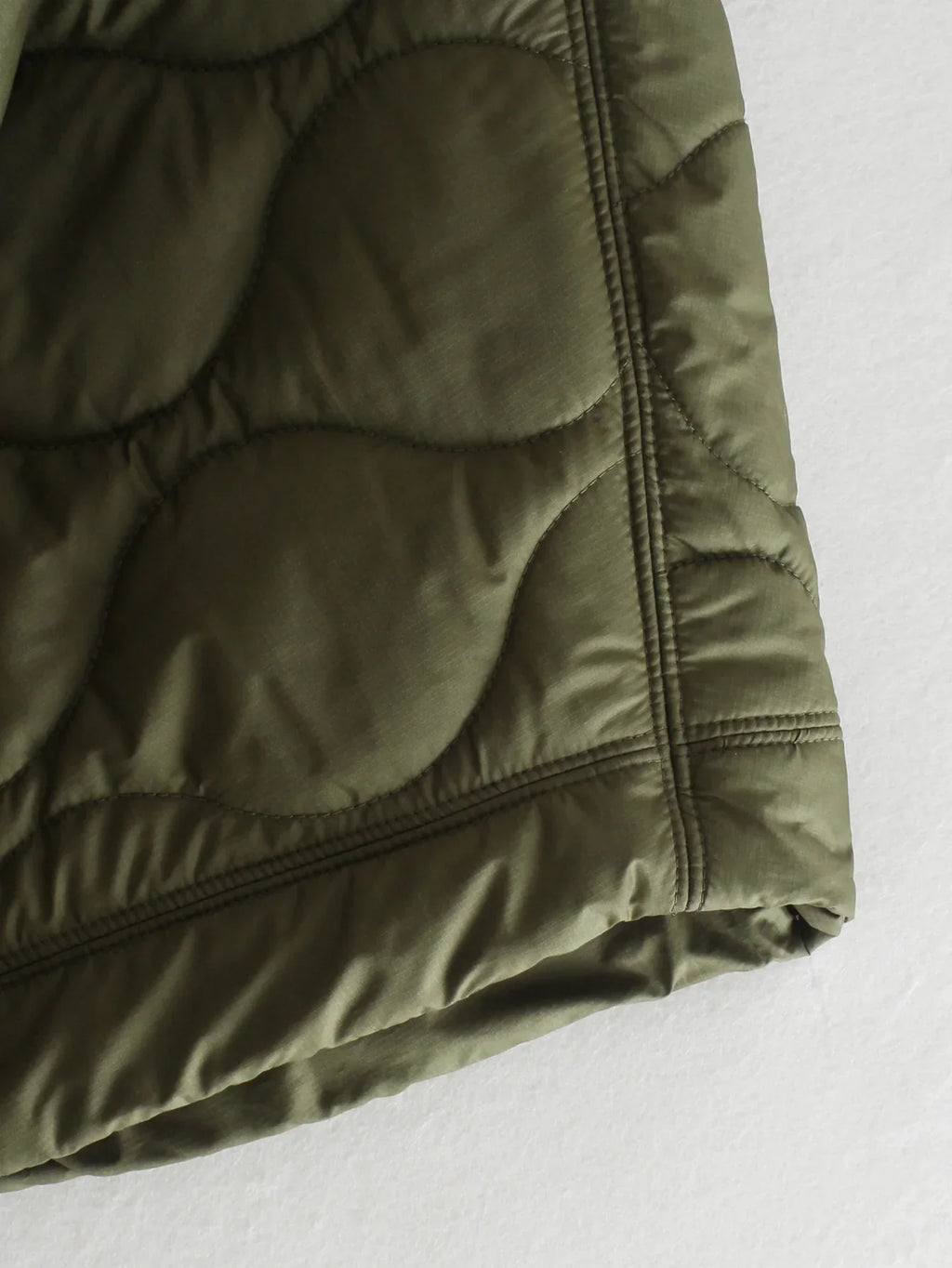 Olive green quilted bodywarmer hem with elastic cuff and side seam stitching