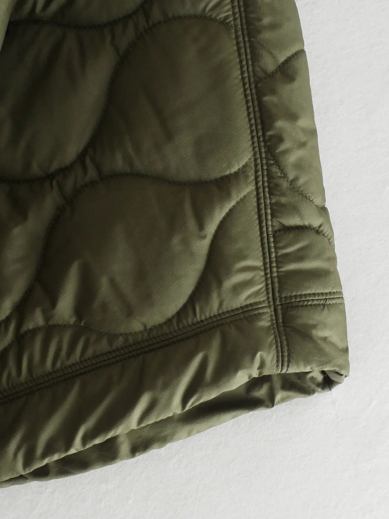 Olive green quilted bodywarmer hem with elastic cuff and side seam stitching