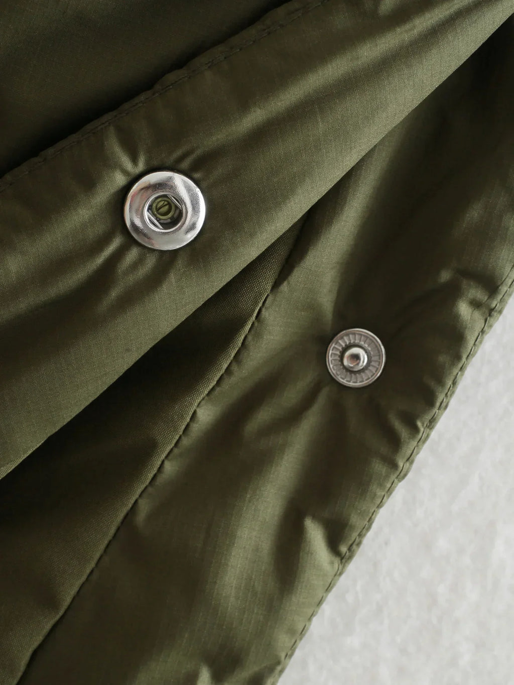 Olive jacket placket with metal snap buttons