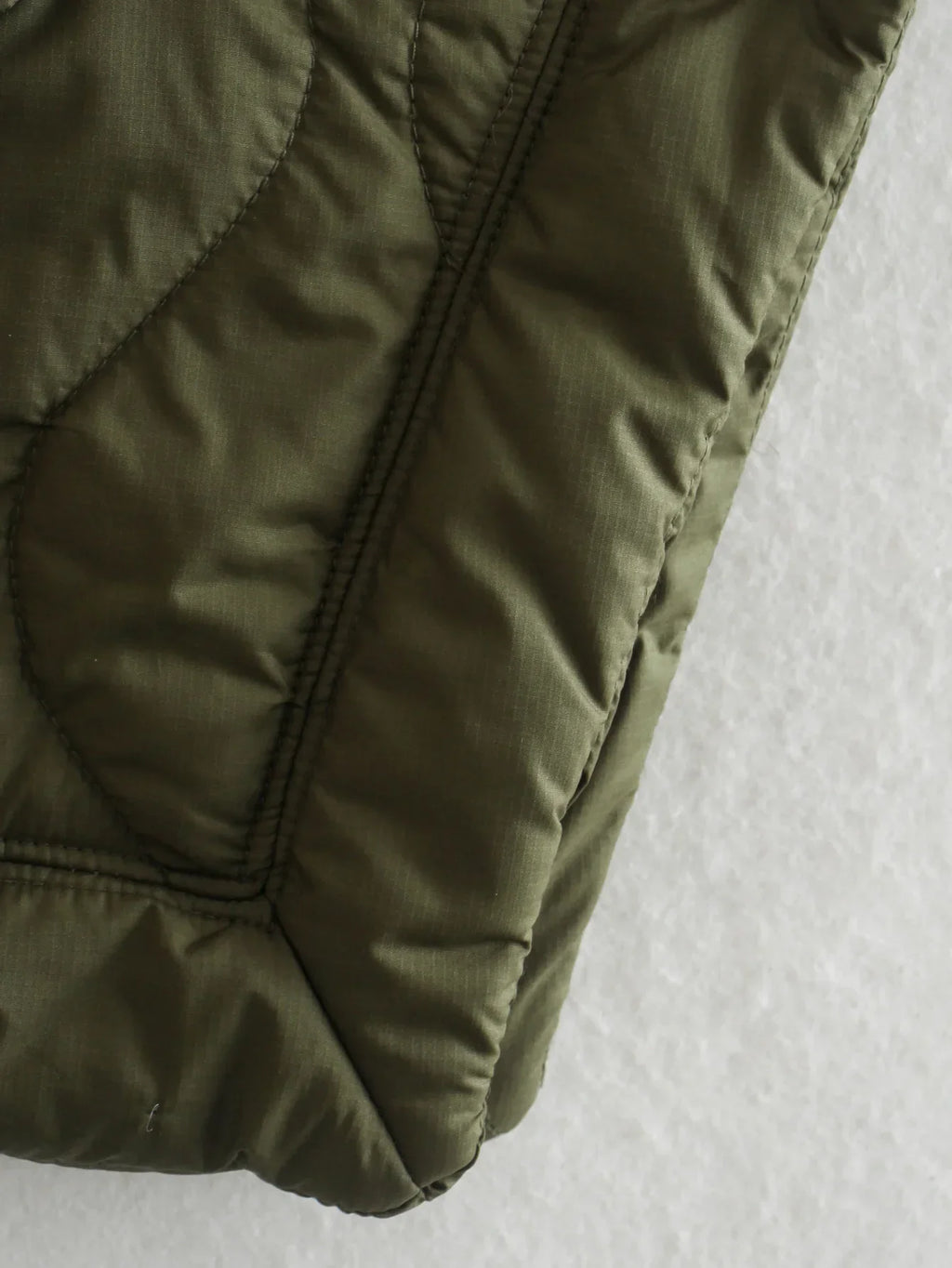 Olive green quilted bodywarmer, ribbed hem and stitched panels detail