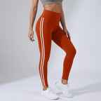 High-waisted orange workout leggings with three white side stripe lines.