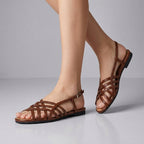 Dark brown woven Roman sandals with crisscross straps and ankle buckle, low block heel