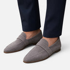 Women's gray suede slip-on loafers with pointed toe and stitched strap detail.