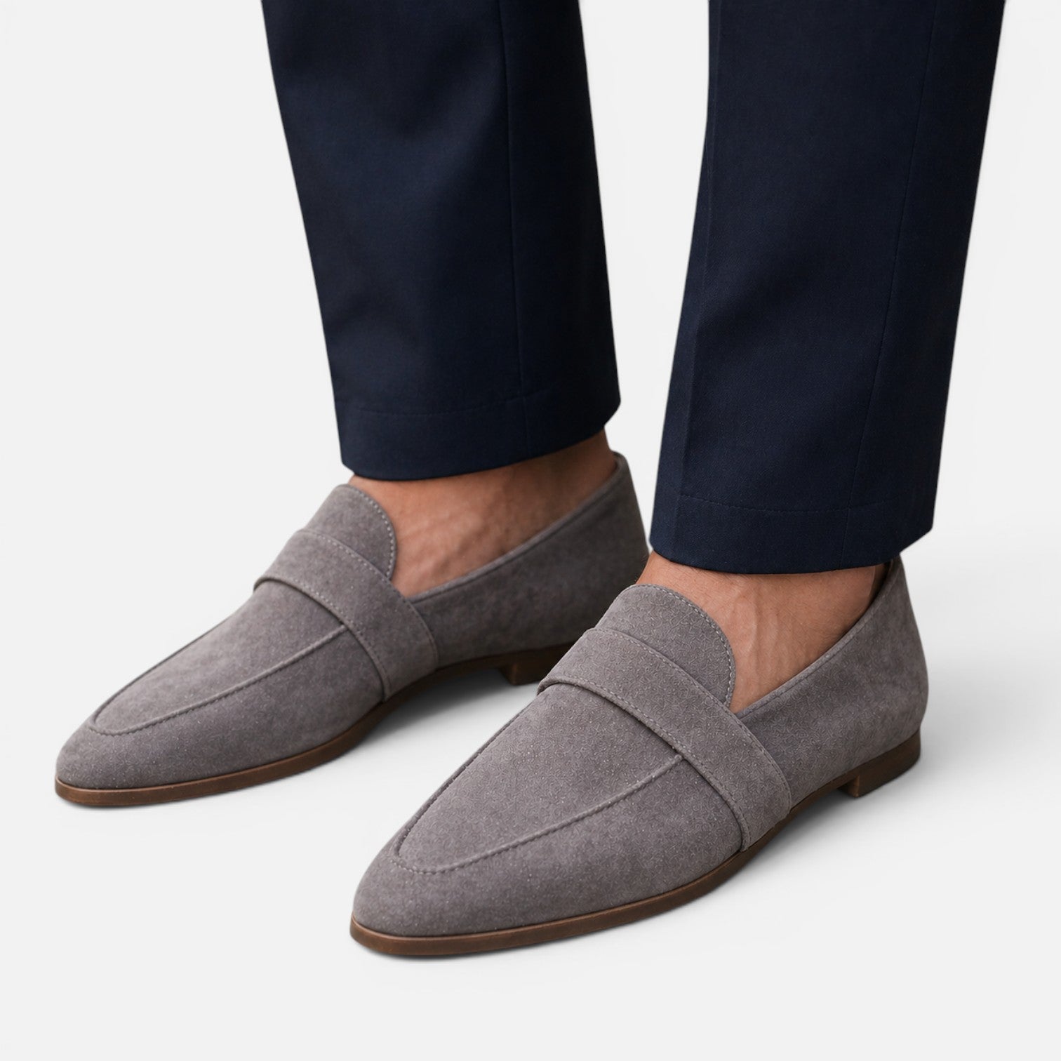 Women's gray suede slip-on loafers with pointed toe and stitched strap detail.
