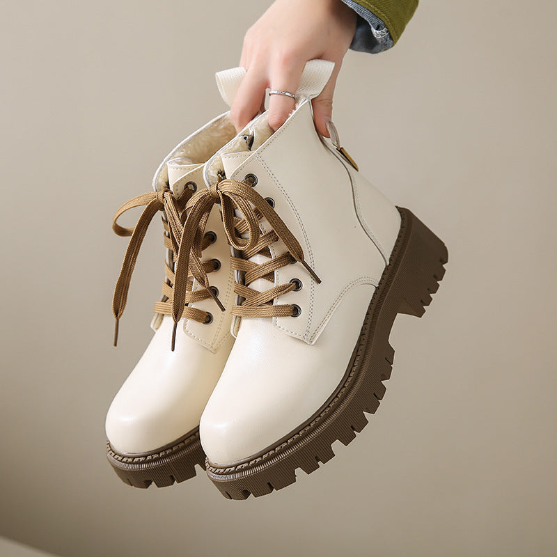 Women's white lace-up side-zip boots held by hand, rugged tread sole