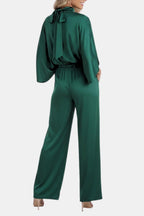 Green cape-sleeve jumpsuit back view with tie neck and cinched elastic waist.