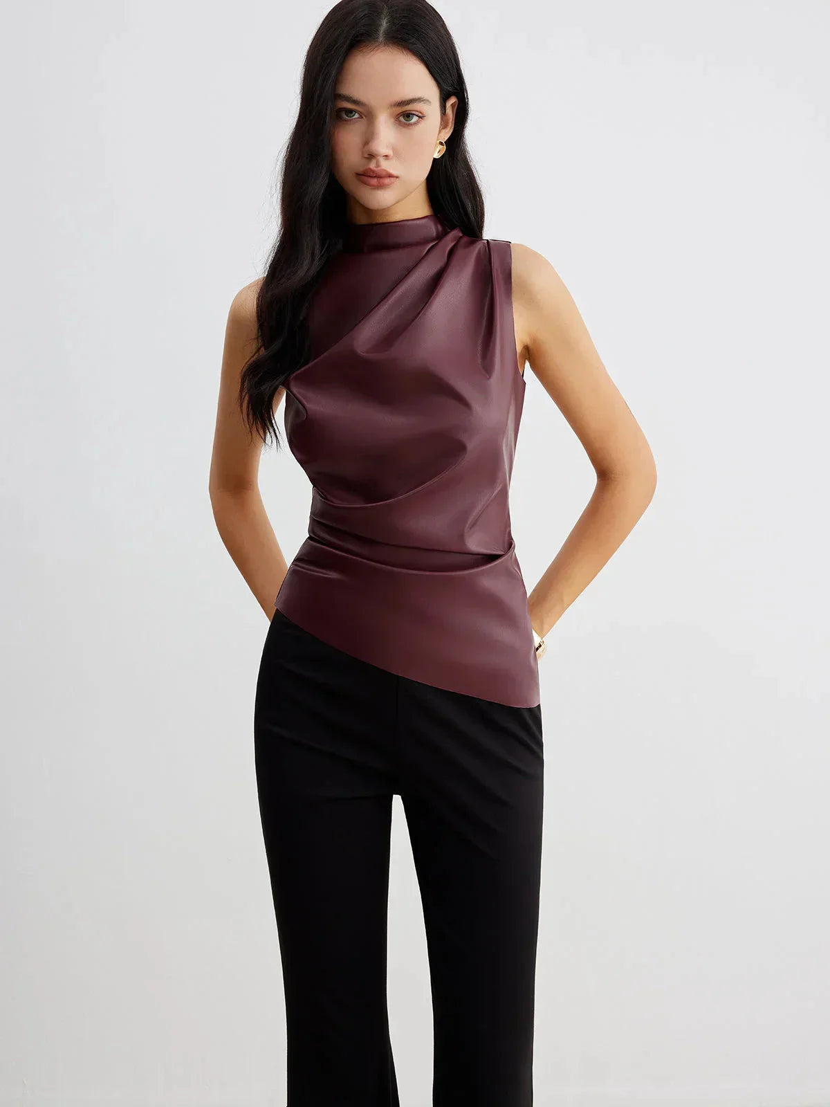 Burgundy sleeveless faux leather mock-neck top with fitted waist and draped front