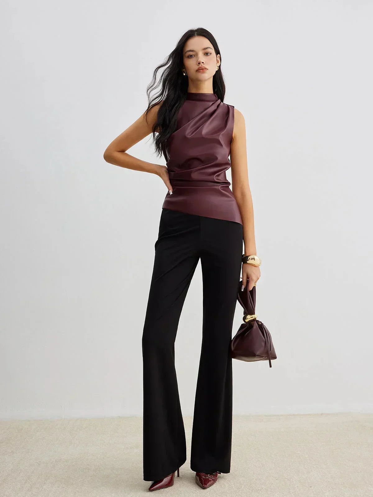 Burgundy sleeveless faux leather mock-neck top with high neckline and fitted drape front