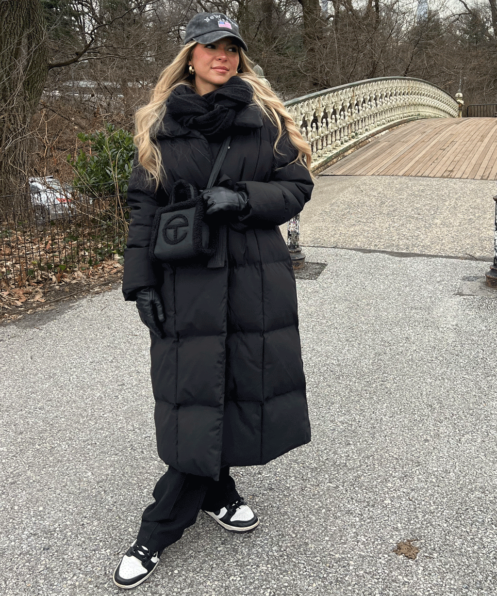 Women's long black puffer coat with hood, belted waist and quilted texture