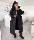 Women's long black puffer coat with hood and belted waist, quilted insulation