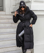Black long puffer coat with hood up and tie belt, quilted quilting and draped side