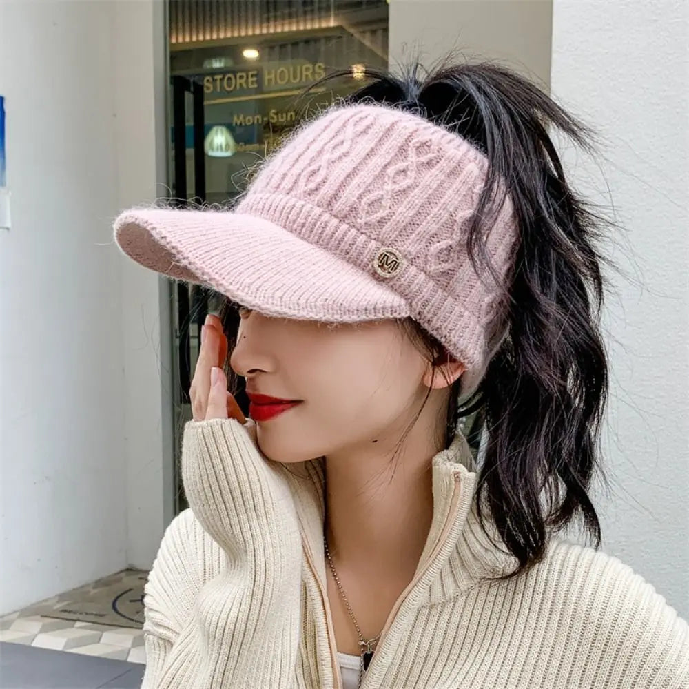 Pink knitted baseball cap with ribbed brim, cable-knit crown, and small M logo badge