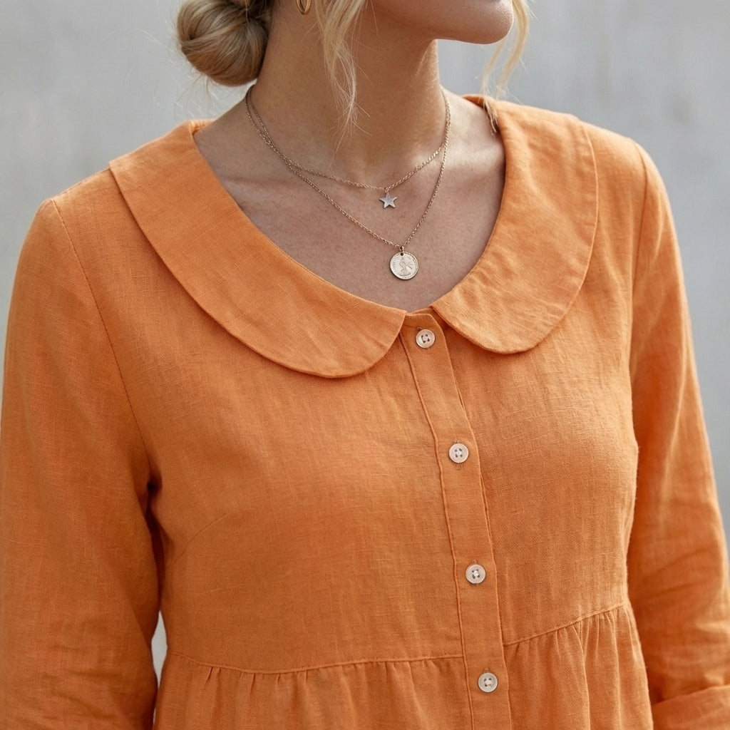 Orange blouse close-up with Peter Pan collar, round buttons, and gathered peplum waist
