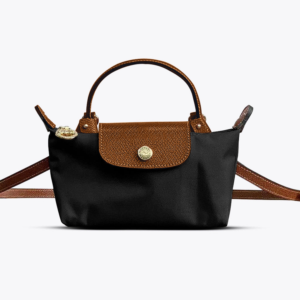 Mini crossbody shoulder bag in black with tan flap and gold-tone clasp, adjustable strap