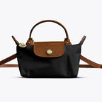 Mini crossbody shoulder bag in black with tan flap and gold-tone clasp, adjustable strap