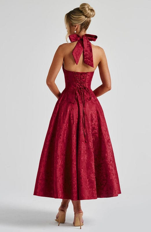 Red sleeveless A-line midi dress, open back with red bow at neckline.