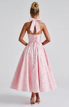Pink sleeveless A-line midi dress, open back with bow tie at upper back.