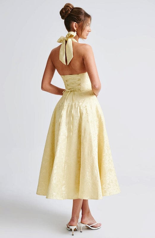 Yellow sleeveless A-line midi dress, open back with bow tie at upper back.