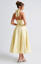 Yellow sleeveless A-line midi dress, open back with bow tie at upper back.