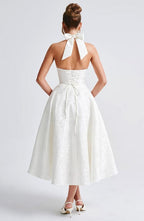 White sleeveless A-line midi dress, open back with bow tie at upper back.