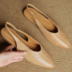 Beige leather slingback flats with pointed toe and cushioned footbed, pair on display