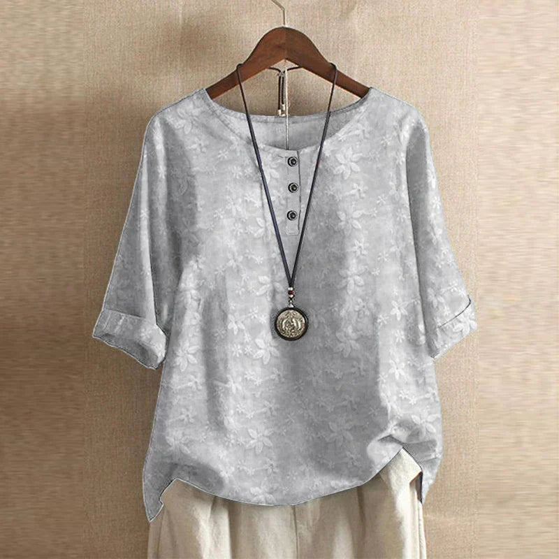Women’s blouse in light gray with subtle floral pattern, short sleeves, button front