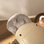 Grey plush ears and cream body of an animal accordion and rattle toy