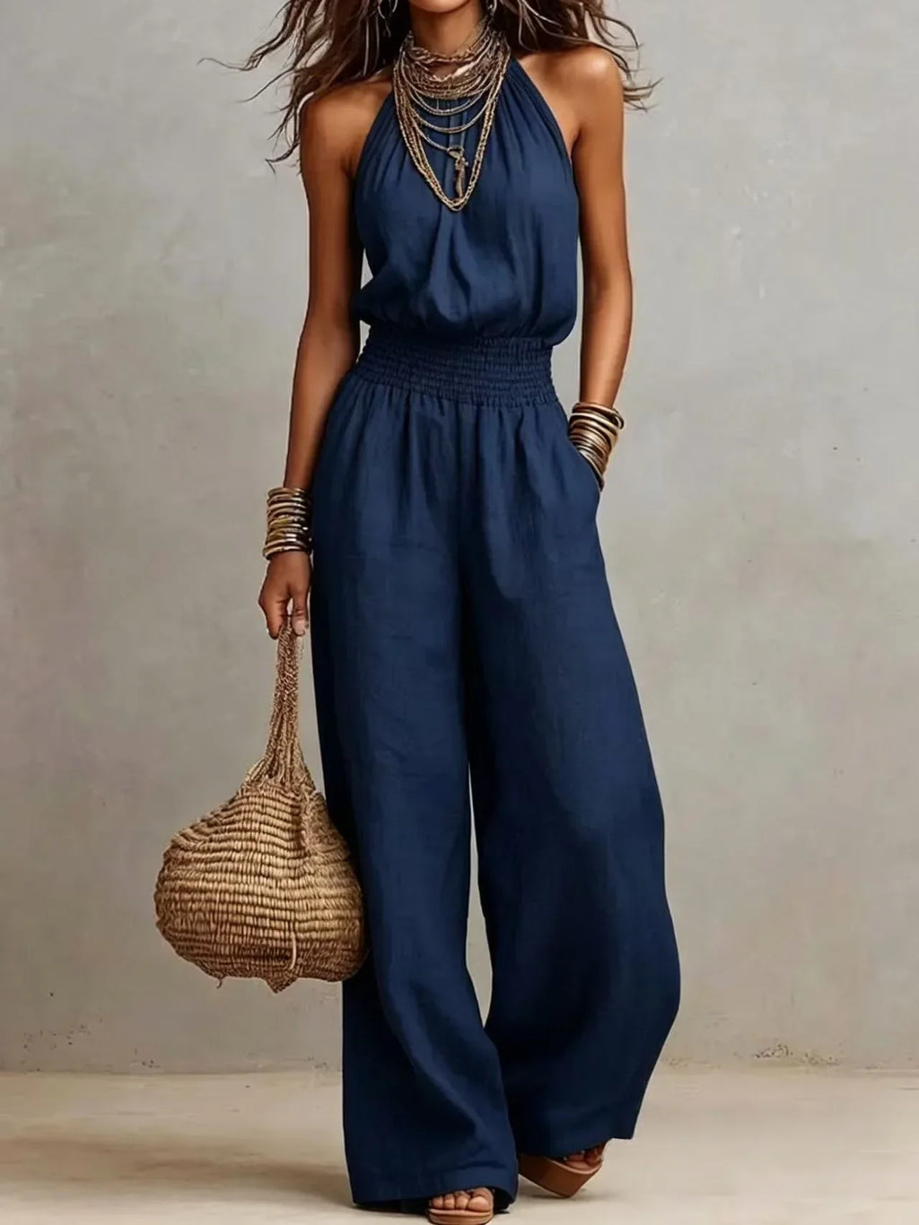 Dark blue sleeveless wide-leg jumpsuit with smocked waist and billowy wide trousers.