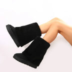 Women’s black tall platform boots with plush cuffs and thick sole, angled side view