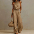 Beige sleeveless wide-leg jumpsuit with smocked waist and loose flowing wide legs.