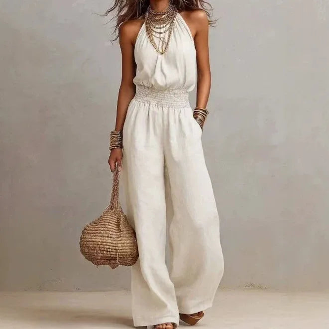 White sleeveless wide-leg jumpsuit with smocked waist and flowing wide trousers.