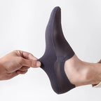 Dark gray no-show socks on foot, hand holding heel area